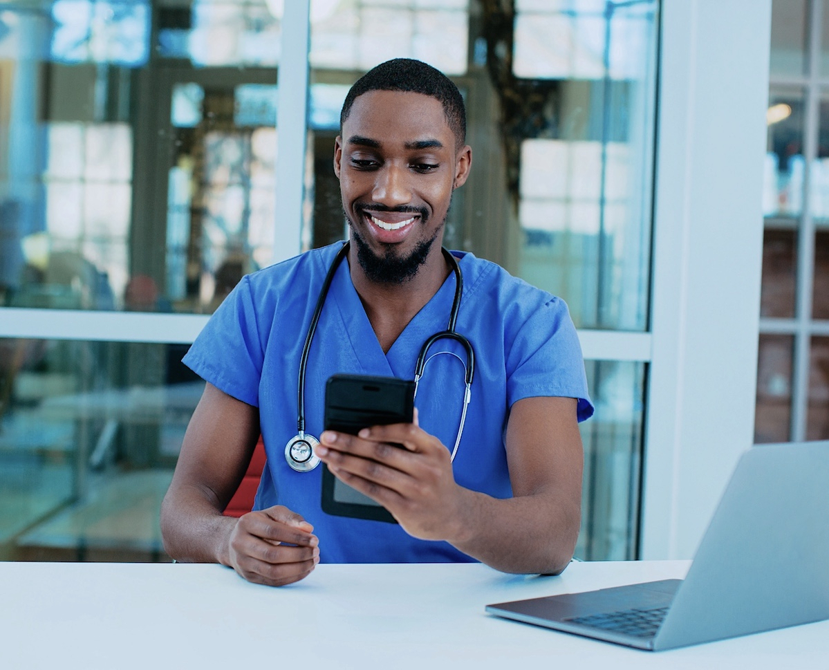 Banner shows a male student nurse using his mobile and laptop for study