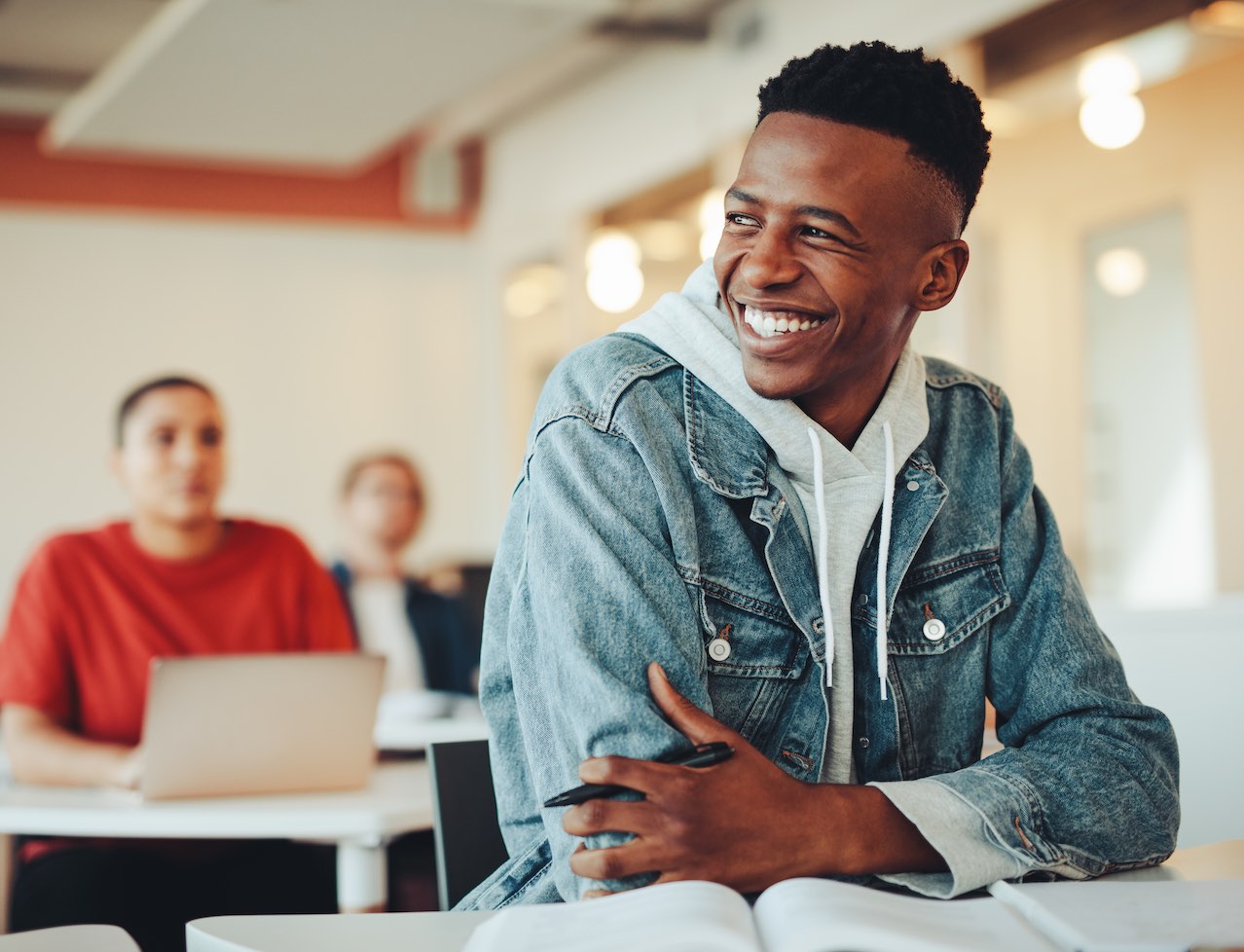 Image shows a picture of a smiling student in a classroom